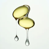 Two droplets of yellow liquid with a third droplet about to join them on a white background