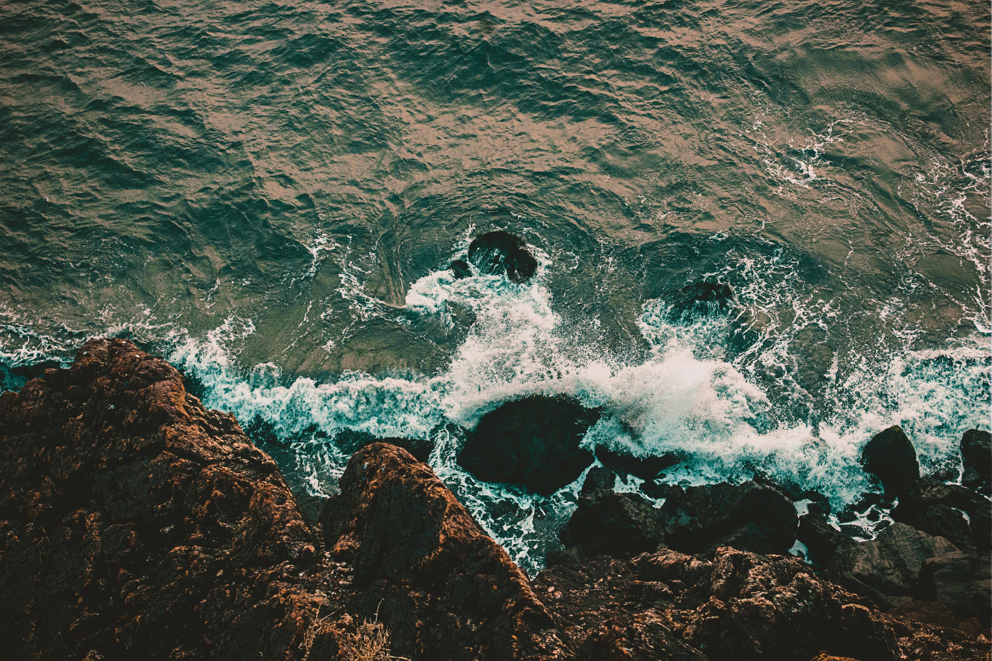 Aerial view of ocean waves crashing on a rocky coastline