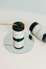Phytoplankton Omega & Multi powder jars with wooden spoon on mirrored surface